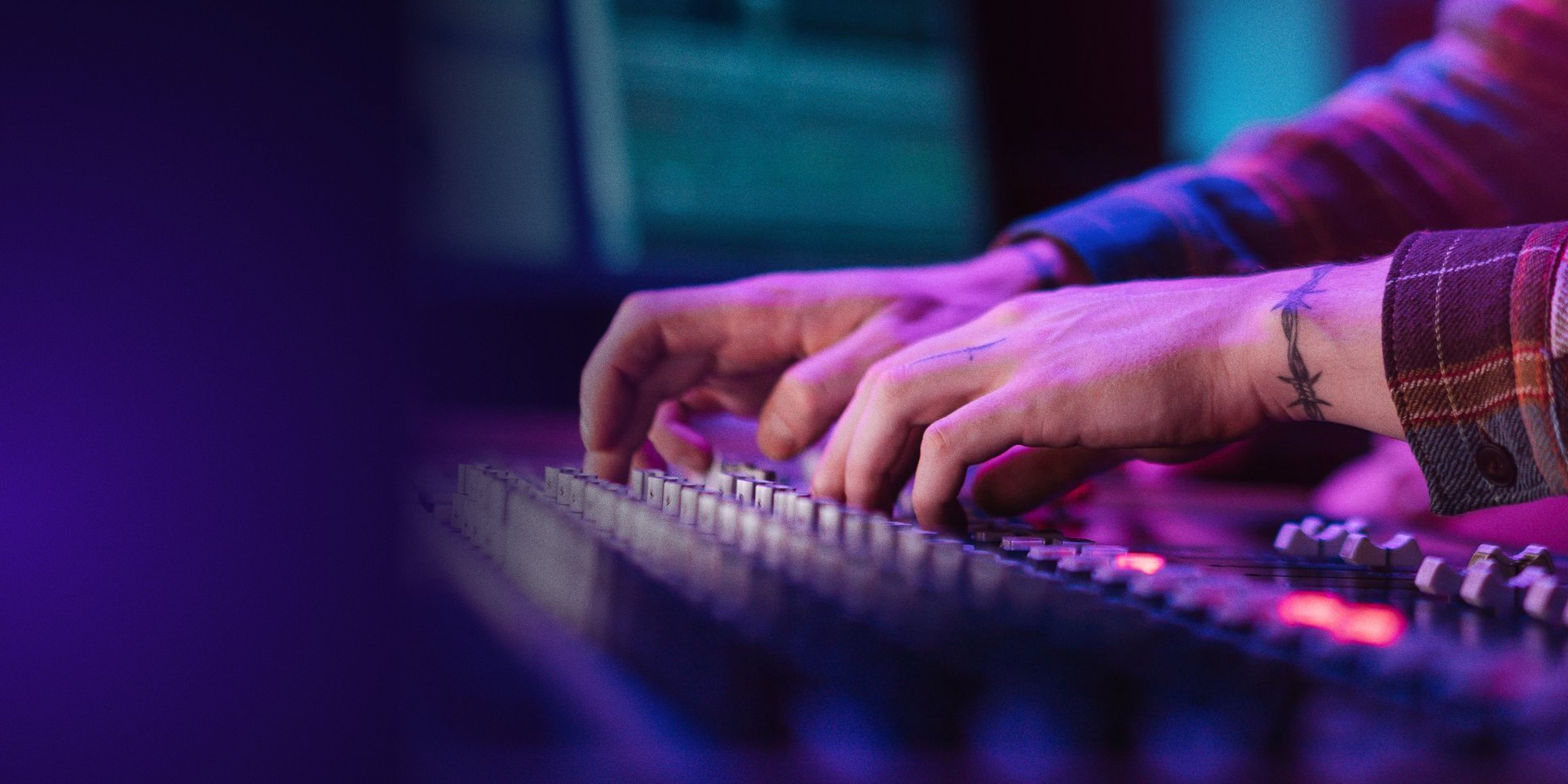 Les mains de deux ingénieurs du son sur la console de mixage, dans la lumière violette de la régie.